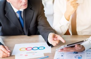 businessman-pointing-finger-digital-tablet-hold-by-his-partner-workplace_23-2147899923