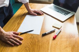 businessperson-s-hand-with-blank-white-paper-wooden-desk_23-2147838598-3