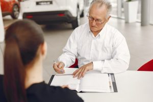 old-man-sitting-car-salon-talking-with-manager_1157-32001