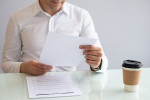 close-up-smiling-young-businessman-looking-document_1262-16924-1